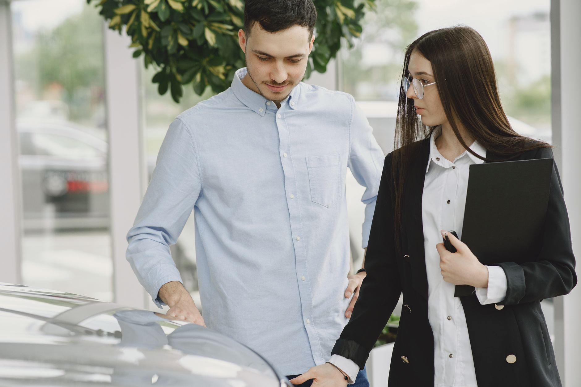 Interaction professionnelle entre un client et un vendeur dans une concession automobile.