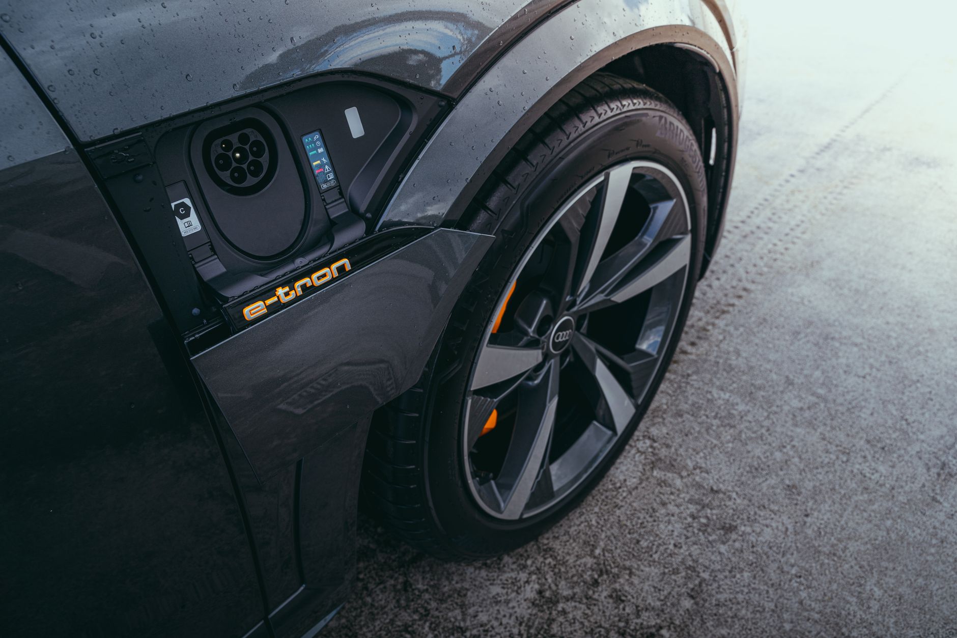 Gros plan sur la trappe de recharge ouverte et une roue avant de voiture électrique